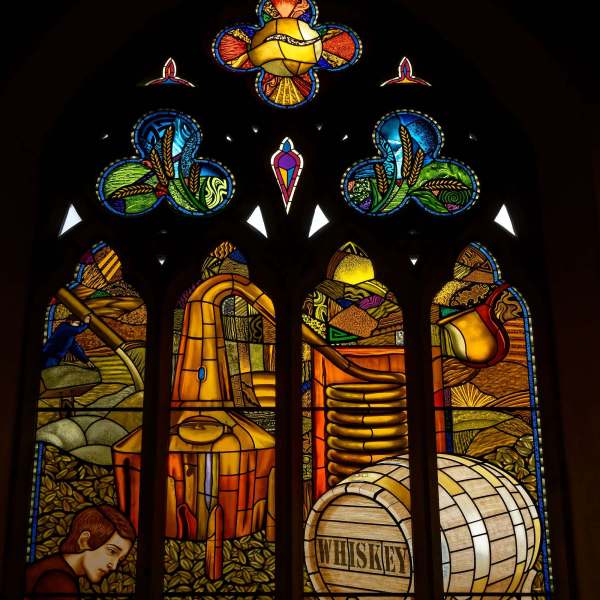 Buntes Kirchenfenster mit Motiven einer Whisky-Destillerie